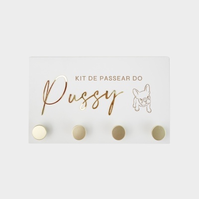 Placa branca com texto dourado KIT DE PASSEAR DO Pussy e ilustração de cão com ganchos dourados.
