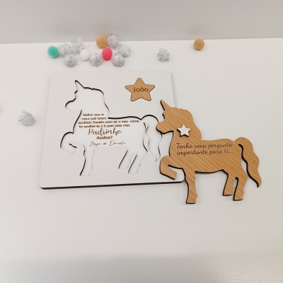 Puzzle de madeira em forma de unicórnio com texto gravado e pompons coloridos ao redor