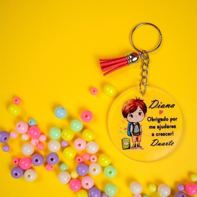 Porta-chaves redondo transparente com imagem de menino e texto em amarelo com contas coloridas