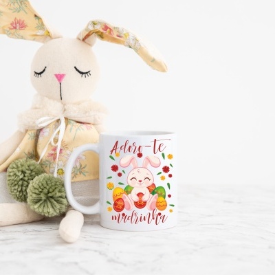 Caneca branca com coelho desenhado e boneco de coelho de tecido ao lado