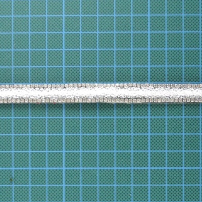 Fita decorativa branca texturizada sobre fundo verde quadriculado azul