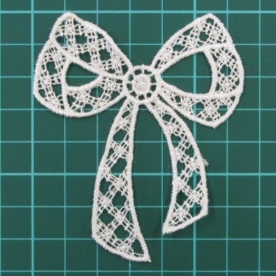 Laço branco em renda sobre fundo verde quadriculado