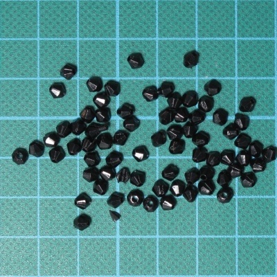 Contas pretas facetadas sobre fundo verde com grelha branca