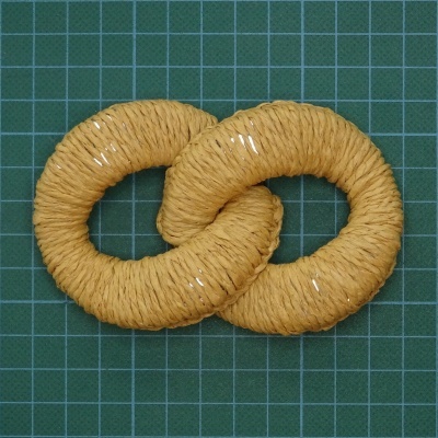 Anel entrelaçado amarelo de corda sobre superfície verde quadriculada