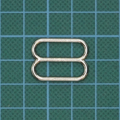 Fivela metálica dupla prateada sobre fundo quadriculado verde e azul