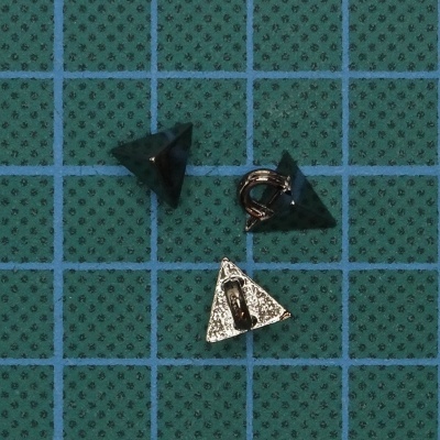 Três pinos triangulares metálicos sobre fundo verde com quadrícula azul