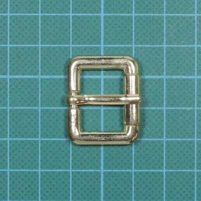 Fivela quadrada metálica dourada sobre superfície verde quadriculada