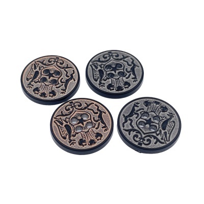 Quatro botões redondos com padrão de caveira em tons cobre e prata