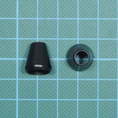 Dois pequenos objetos pretos, um cónico e outro em forma de anel, sobre superfície quadriculada azul.