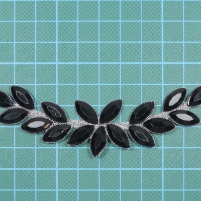 Pulseira ou colar decorativo com peças em formato de folhas pretas e prateadas.