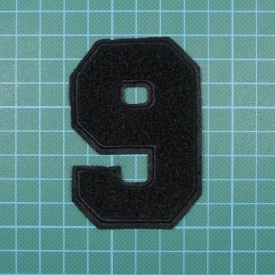 Número 9 preto de tecido felpudo sobre fundo quadriculado azul claro