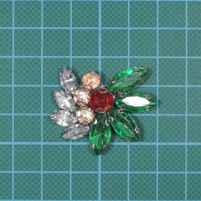 Broche com pedras coloridas sobre fundo de grid azul.