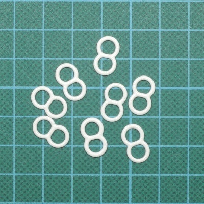 Argolas brancas em forma de oito sobre grelha verde com linhas azuis
