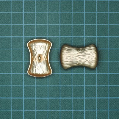 Dois botões castanhos texturizados sobre superfície quadriculada verde.