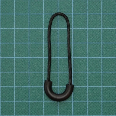 Elástico preto com parte rígida curvada em plástico sobre base quadriculada verde