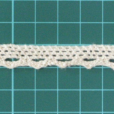 Renda branca de algodão com padrão e borda ondulada sobre superfície verde