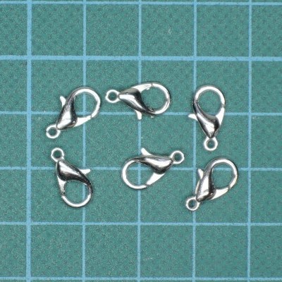 Seis fechos de lagosta metálicos prateados sobre fundo verde com grade azul clara