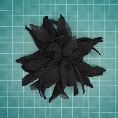 Flor decorativa preta em tecido sobre base verde quadriculada