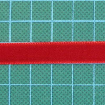 Fita de cetim vermelha sobre superfície verde com grelha quadriculada azul