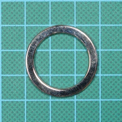 Anel metálico prateado sobre fundo verde com padrão de grade azul clara.