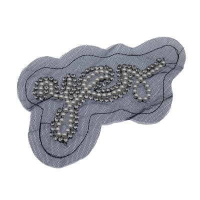 Aplicação em tecido cinza com pérolas formando palavra 'yes' em letra cursiva
