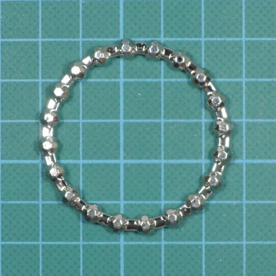 Pulseira metálica prateada em superfície azul com grelha