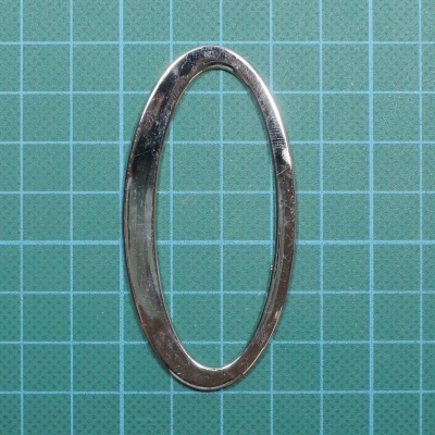 anel oval metálico prateado sobre superfície verde quadriculada