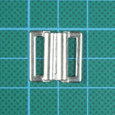 Fecho metálico prateado sobre superfície quadriculada verde