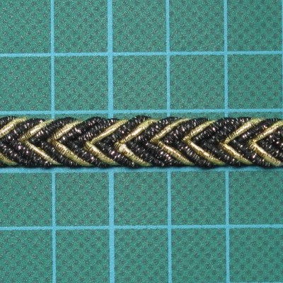 Fita decorativa preta e dourada com padrão em chevron sobre superfície azul com grade.