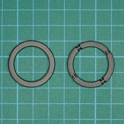 Dois anéis metálicos cinzentos sobre superfície verde com padrão de grade