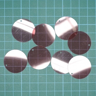 Discos metálicos redondos espelhados sobre superfície de corte verde com grelha