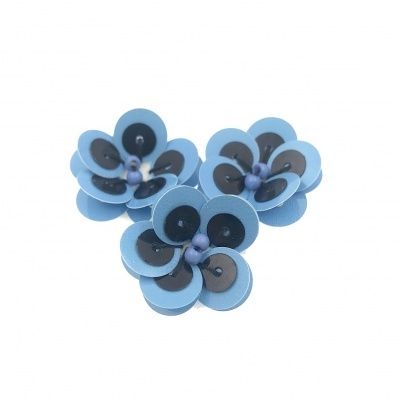 Três flores artificiais azuis claras com detalhes castanhos e pretos