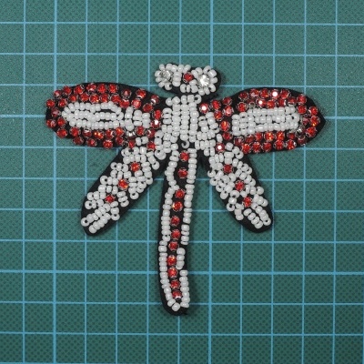 Aplicação decorativa de libélula feita de pedras vermelhas, brancas e pretas