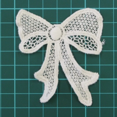 Laço branco em renda com textura vazada sobre fundo verde com grelha branca