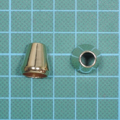 Dois elementos metálicos dourados cónicos sobre superfície quadriculada verde e azul