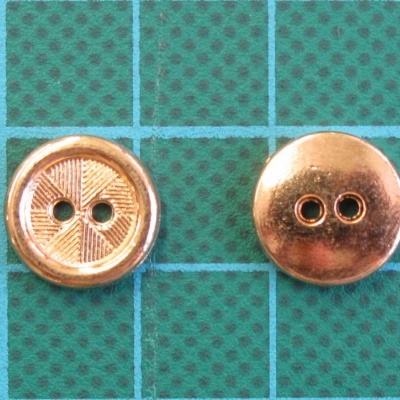 Dois botões metálicos cobre com dois orifícios sobre fundo verde de grade azul