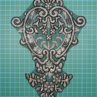 Aplique de renda bordada flores e arabescos pretos e cinzentos sobre superfície azul com grade