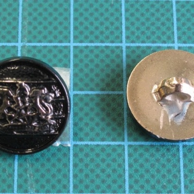 Dois botões metálicos redondos, um preto brilhante com relevo e outro dourado liso, sobre fundo quadriculado azul.