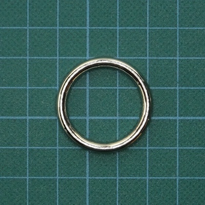 Anel metálico prateado circular sobre fundo verde com grelha branca