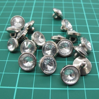 Botões decorativos redondos com centro transparente e borda prateada em superfície verde com grelha