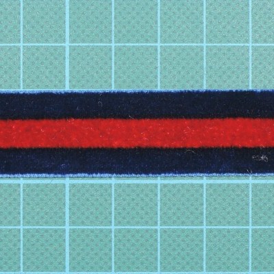 Fita têxtil vermelha e azul com padrão listrado sobre superfície quadrícula azul.