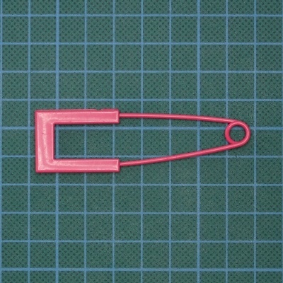 Alfinete de segurança rosa sobre fundo quadriculado verde