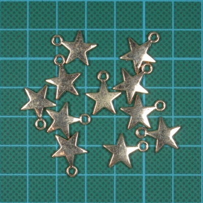 Pendentes prateados em forma de estrela sobre superfície verde com grelha azul