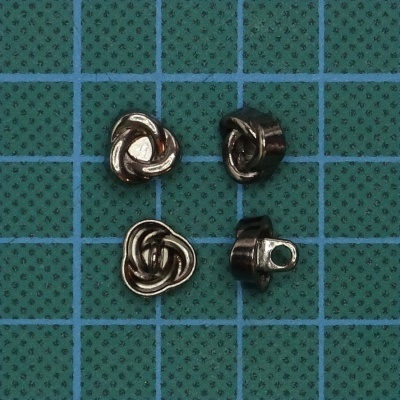 Peças metálicas pequenas com padrão de nó em fundo quadriculado verde.