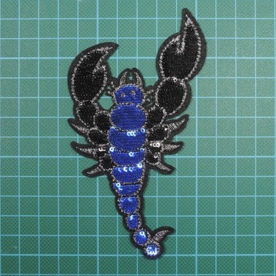 Aplicação em forma de escorpião azul e preto sobre fundo verde quadriculado