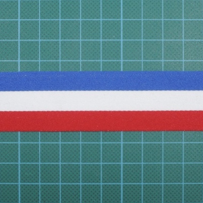 Três fitas azuis, brancas e vermelhas sobre superfície verde com grelha.