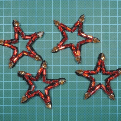 Quatro estrelas decorativas vermelhas e douradas sobre fundo azul quadriculado