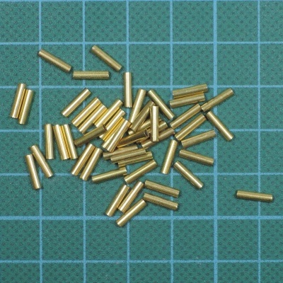 Peças metálicas cilíndricas douradas sobre superfície quadriculada verde