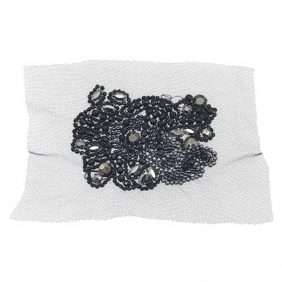 Aplicação decorativa com pedras pretas e transparentes em base de tecido branco