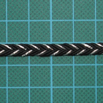 Cabo trançado preto e branco sobre superfície de corte verde com grid azul